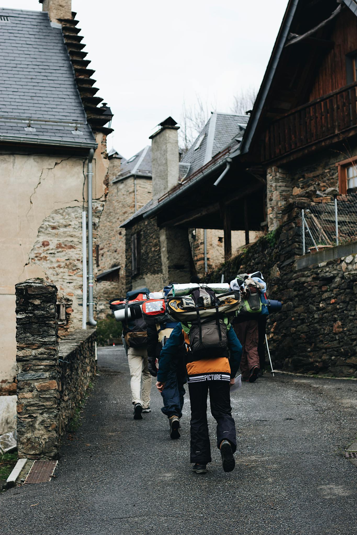 Group of hikers trekking through a picturesque stone-built village street.