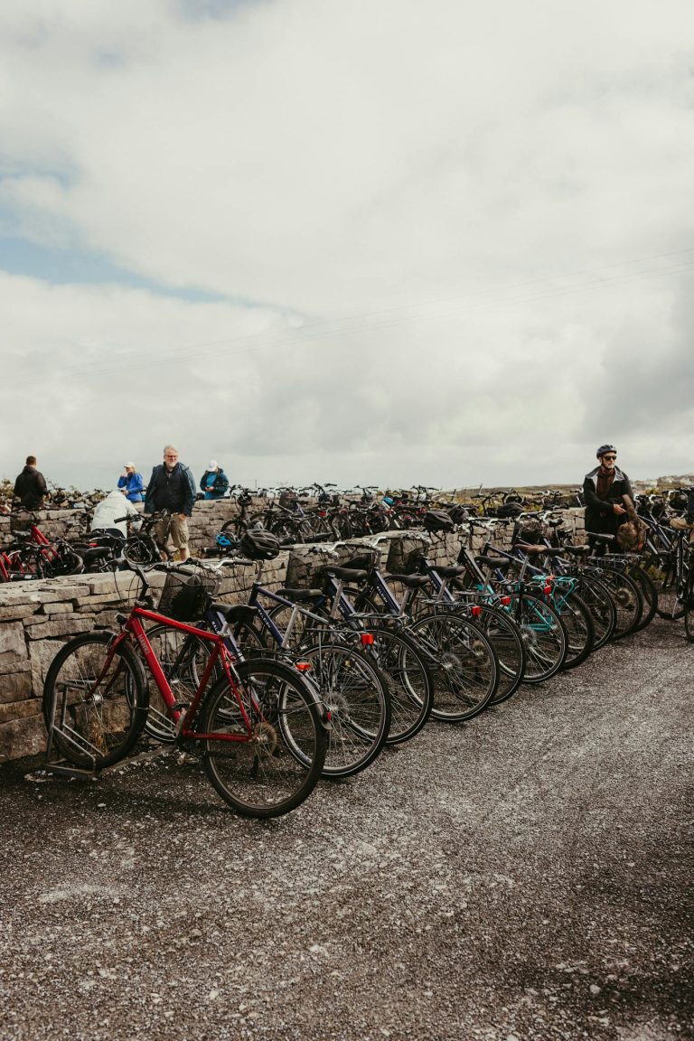 A line of bicycles parked against a stone wall on Inishmore, Ireland, under cloudy skies.