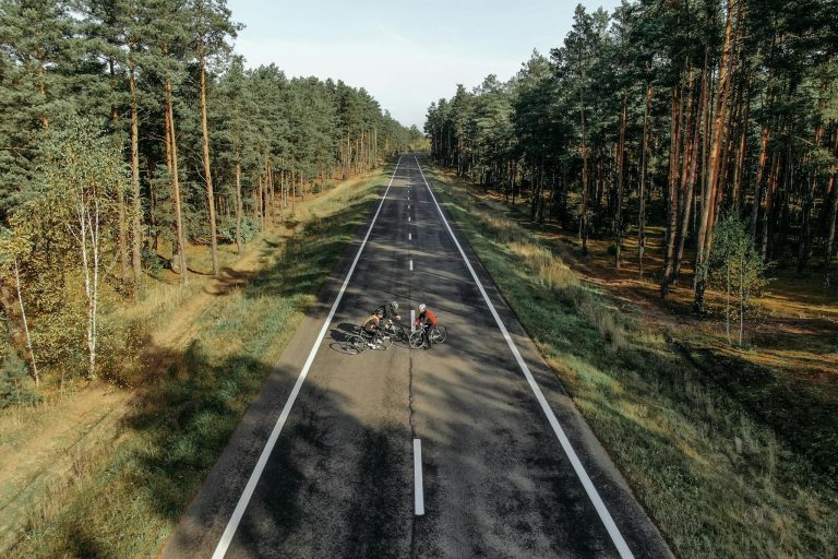 Aerial view of cyclists on an open road in a forested area of Belarus, capturing nature and adventure.