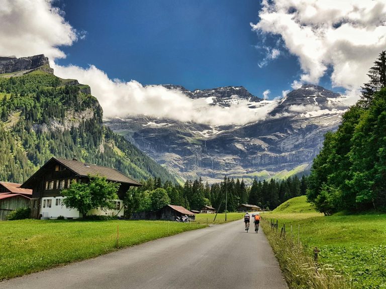 Cyclists ride through the picturesque Swiss Alps in Ollon, surrounded by lush landscapes and towering mountains.